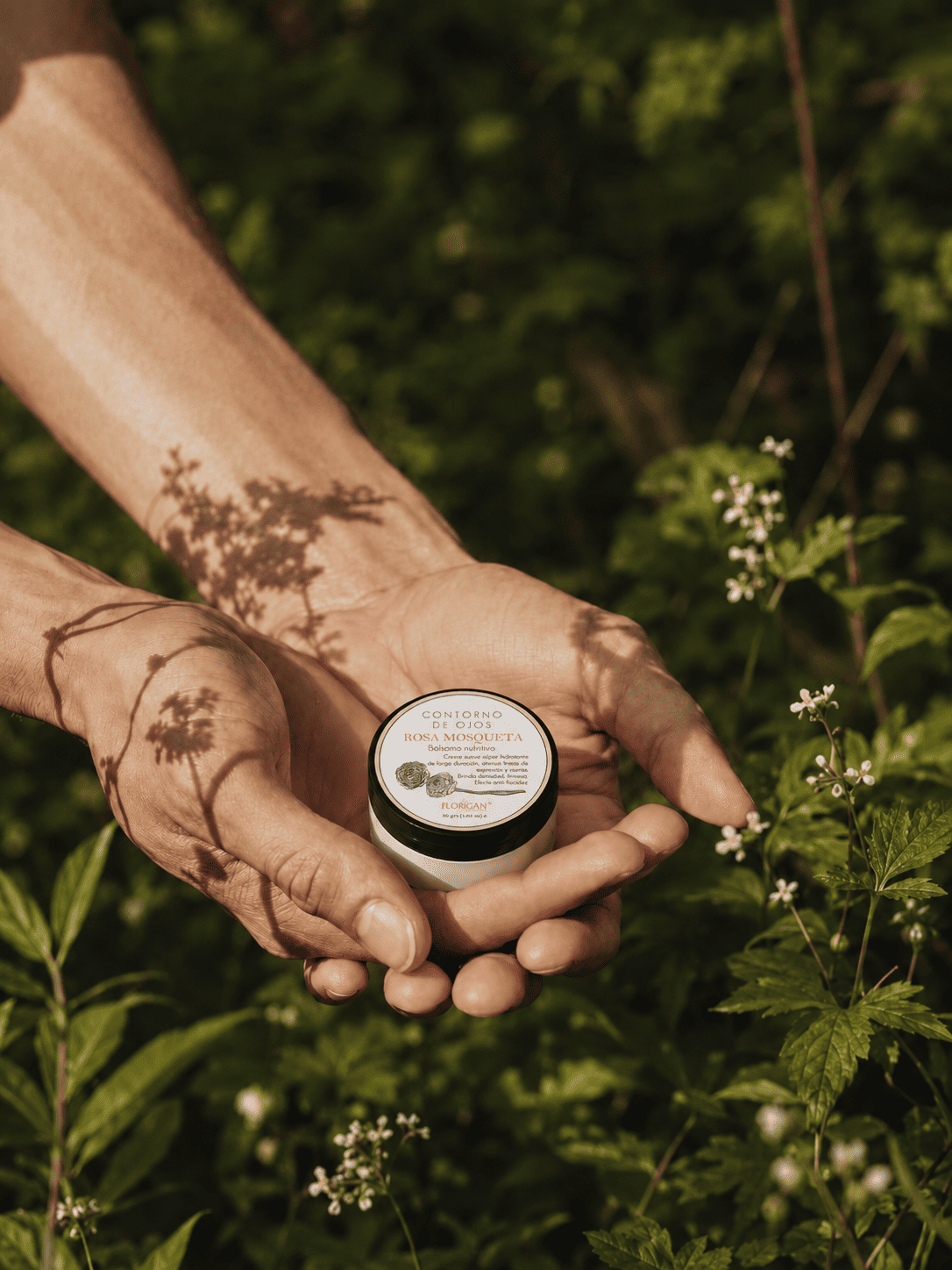Manos sosteniendo un producto Florigan entre plantas y flores